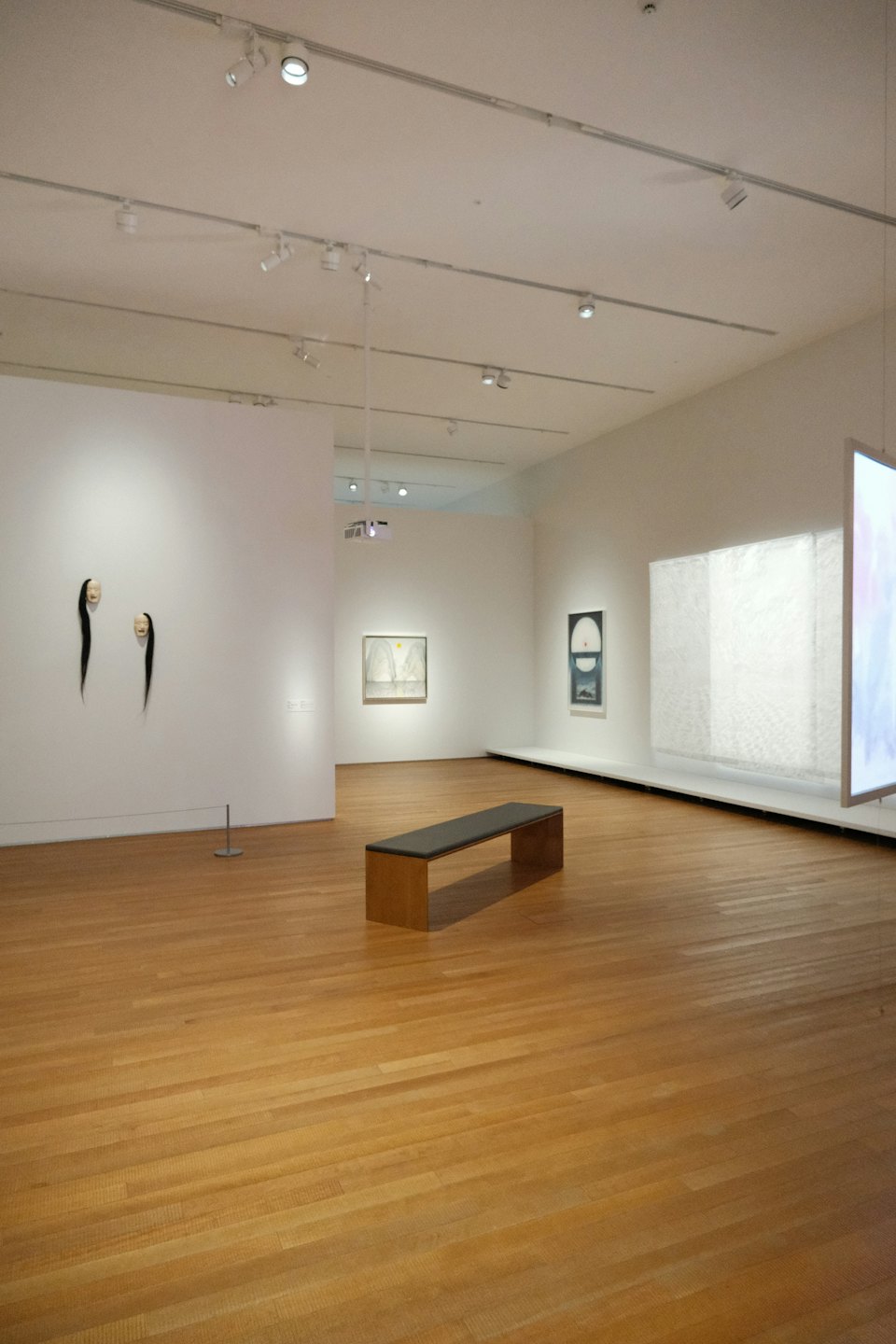 Modern art gallery with abstract wall sculptures and a wooden bench.