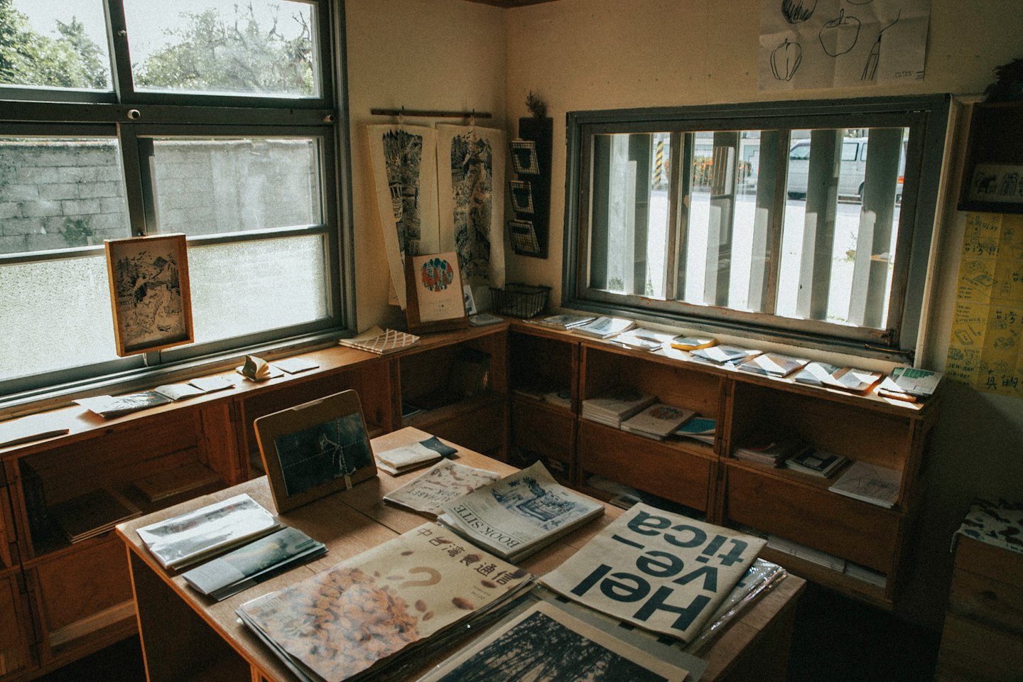 Wooden bookshelves and reading tables filled with newspapers in a library.
